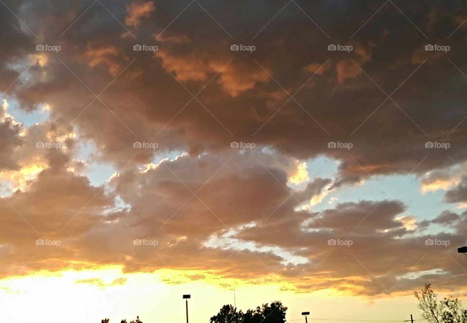 Creamy white ,orange, yellow, blue clouds in front of setting sun