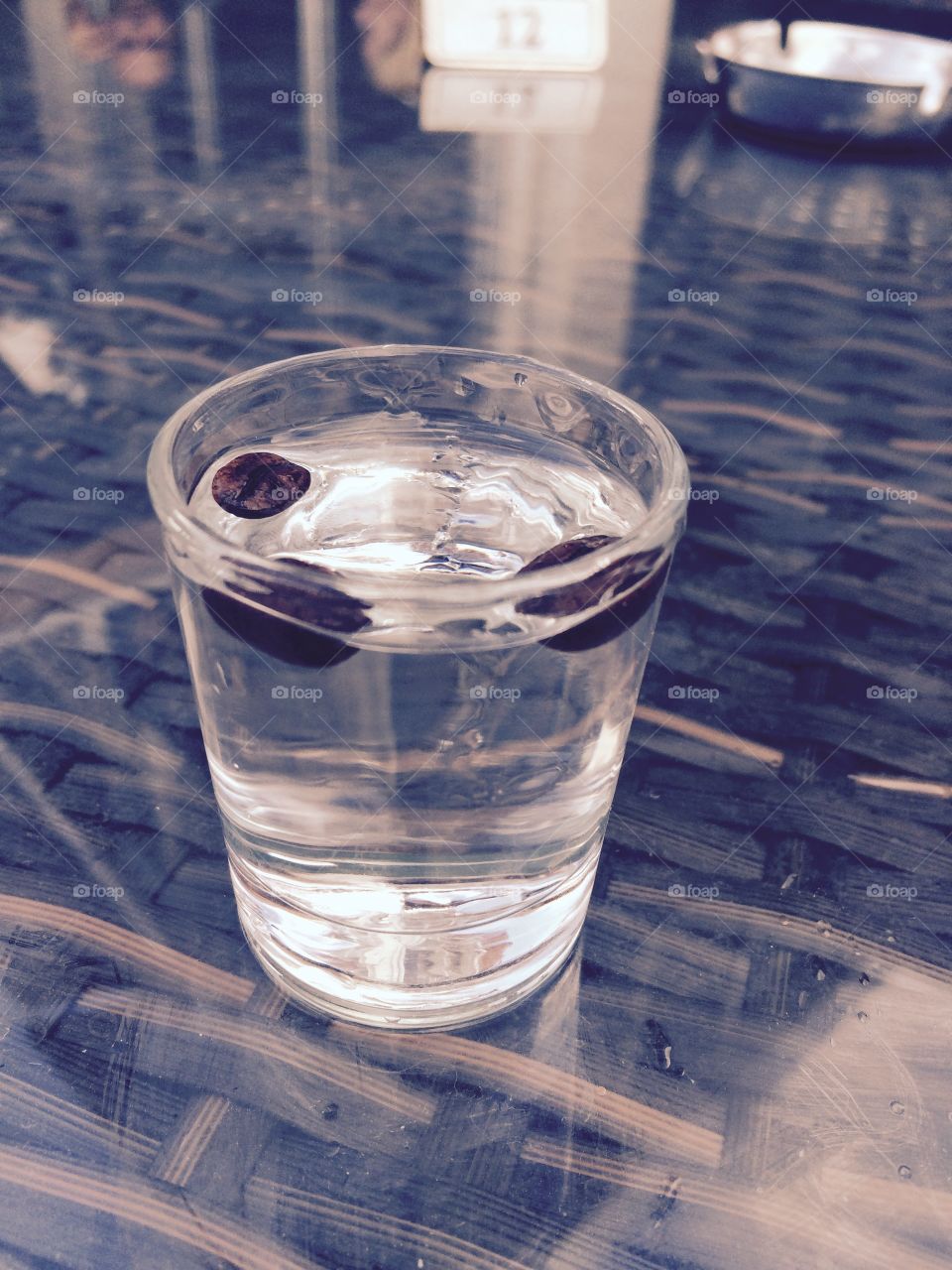 Sambuca shot with coffee beans. Clear shot glass on table, reflection, alcohol