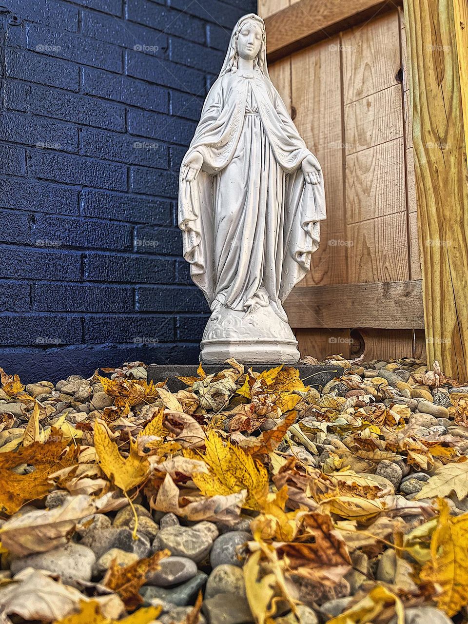 Holy statue in the fall time, leaves surrounding Mary statue, statues outdoors in the fall 