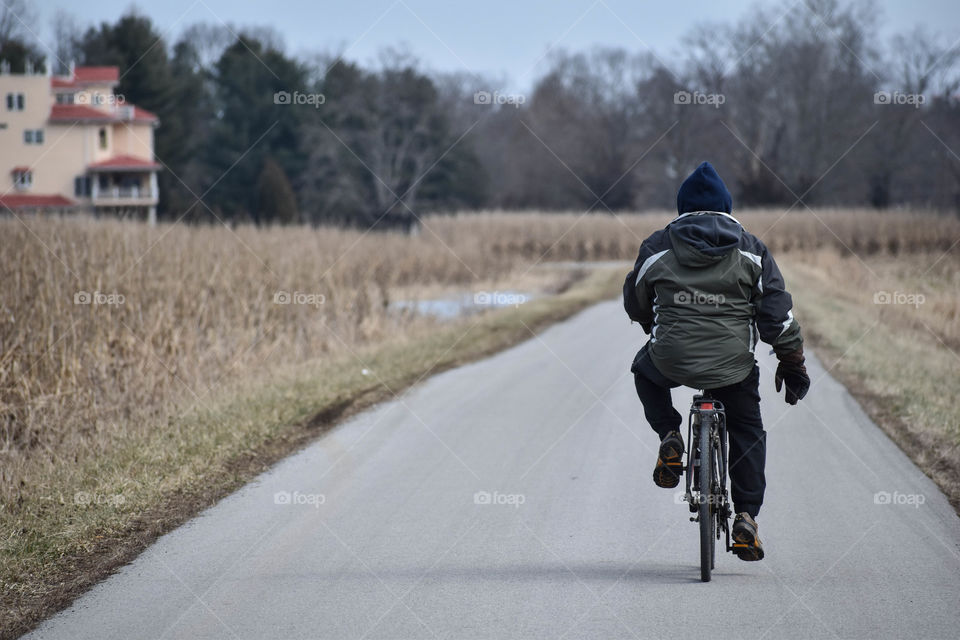 A mid-winter bike ride takes this outdoorsman down a straight road. 