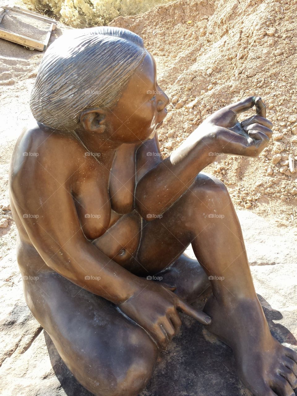 native american bronze. photo taken in New Mexico. woman looking at a kernel of corn