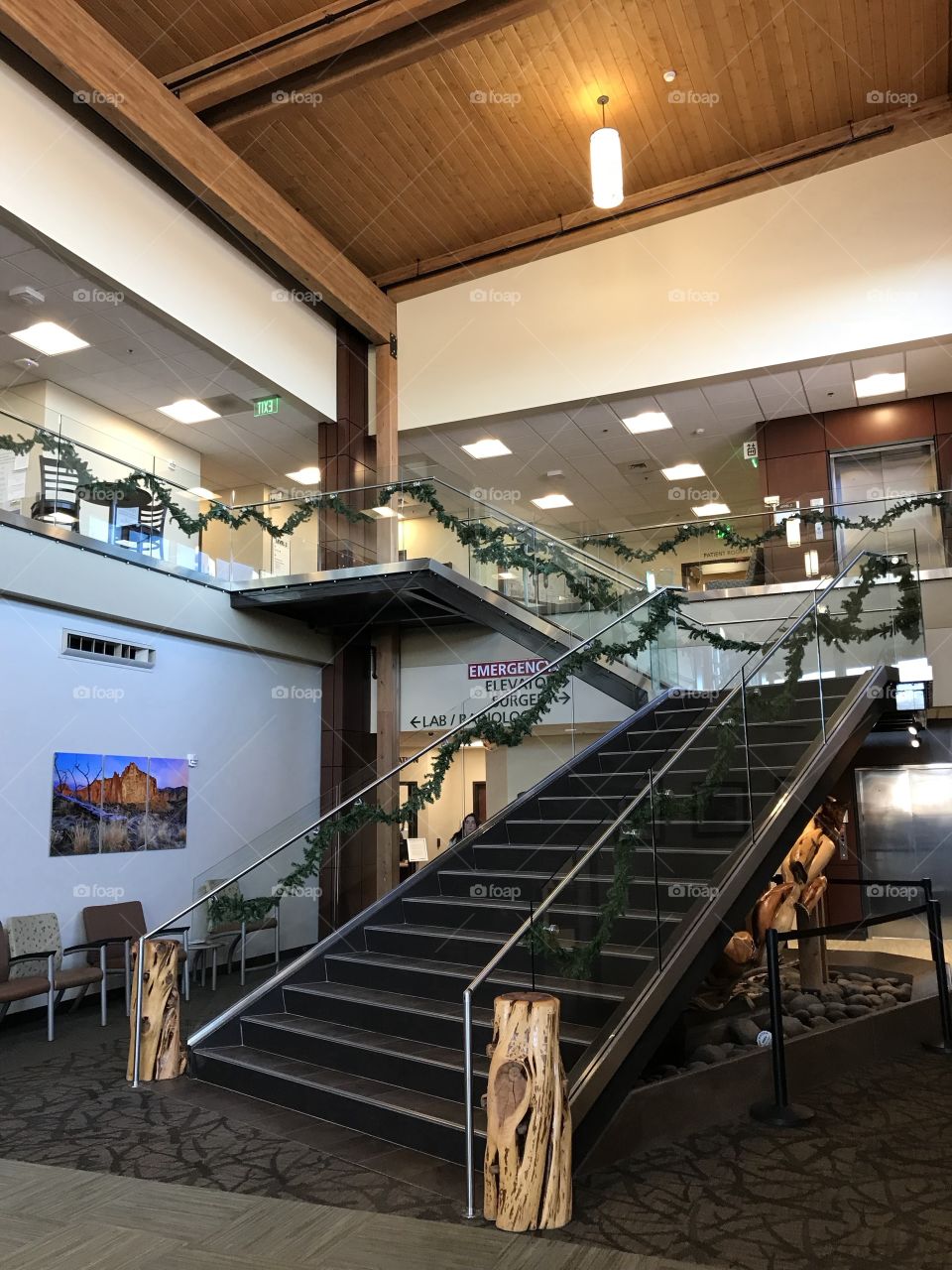 Two levels of stairs leading to an upper floor beautifully decorated with garland for the holiday season. 