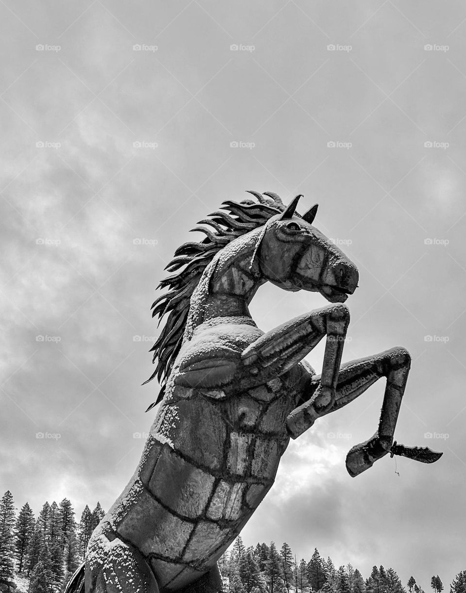 Sculpture of a horse against an overcast sky.