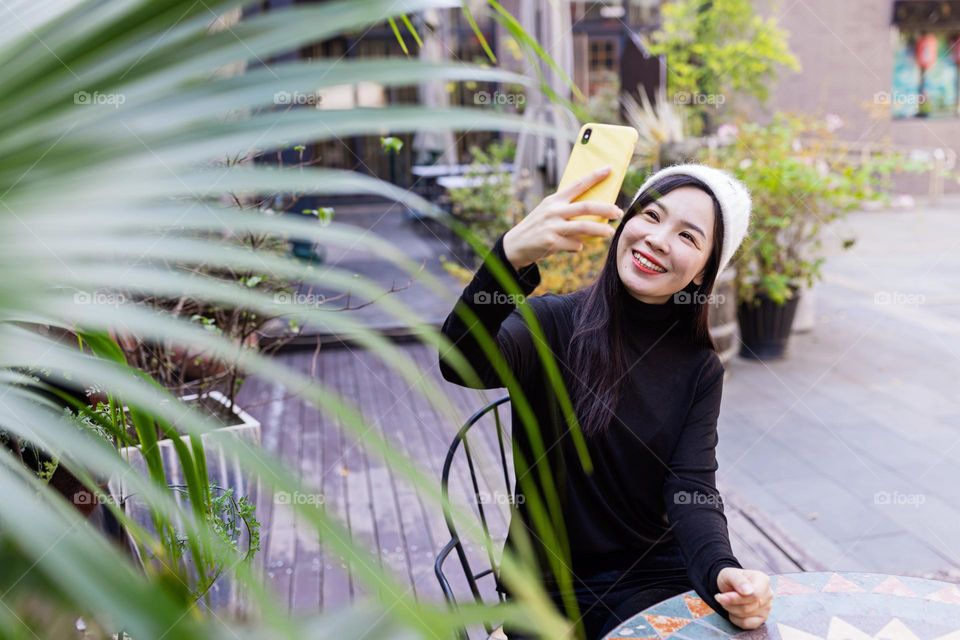 Asian woman influencer using social media via mobile phone outdoor 