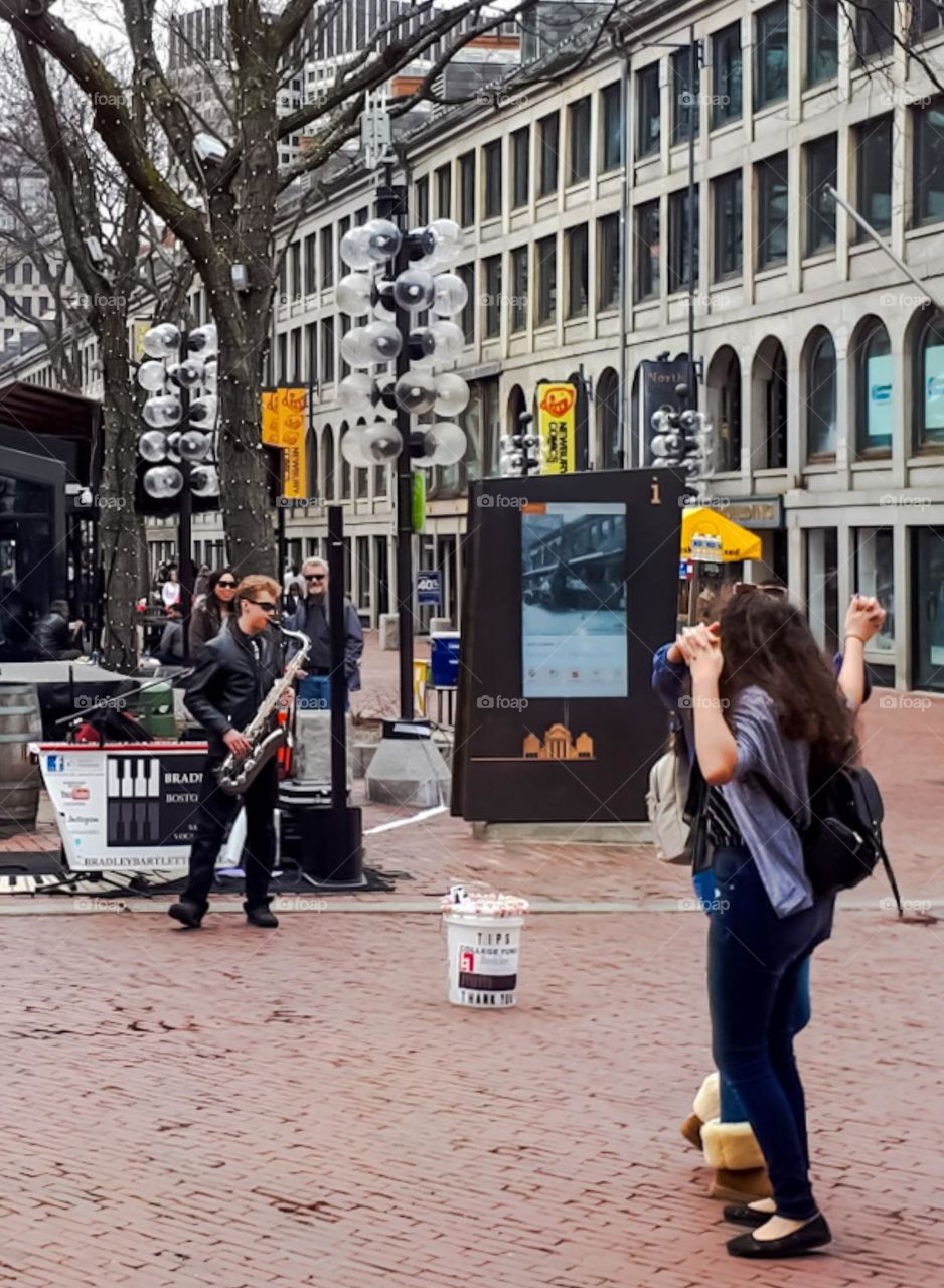 Street Art with Love: Musician plays saxophone on the sidewalk and two women show their love by dancing.
Arte de Rua com Amor: Músico toca saxofone na calçada e duas mulheres demonstram seu amor dançando.