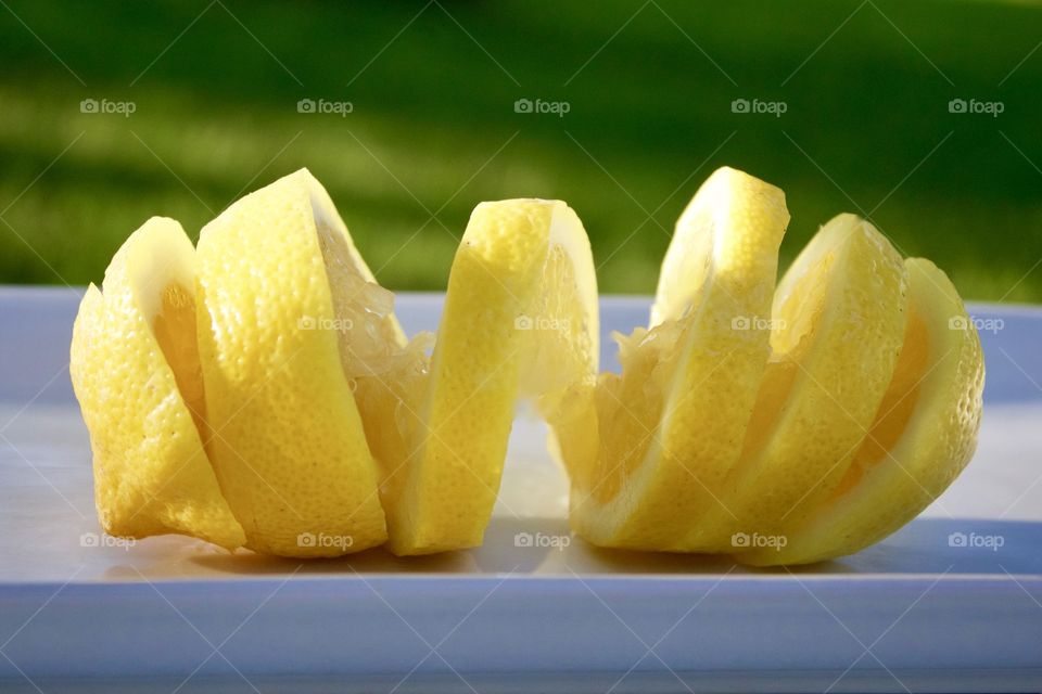 Fruits! - Spiral-cut lemon on a white plate outdoors in sunlight