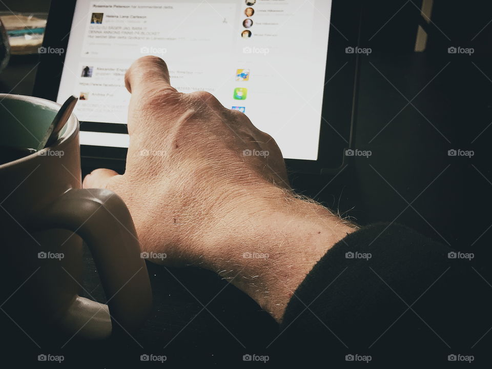 Man using a tablet while drinking coffee