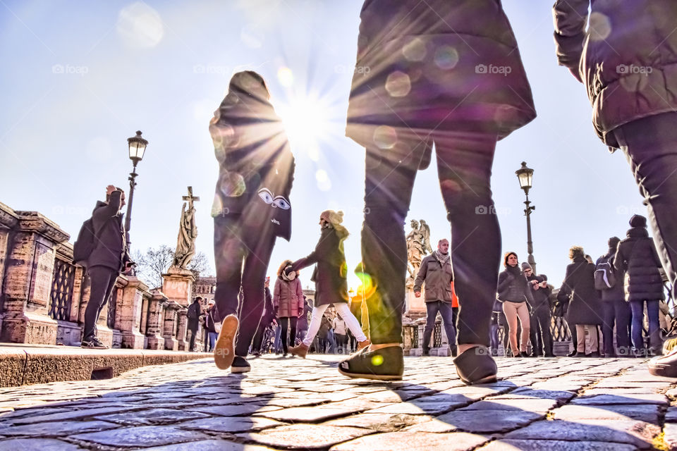 Crowd Of People Walking Under The Sun On City Street