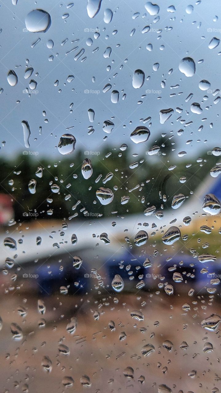 blured airplane wing through the airplane window filled with rain drops