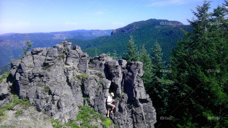 Hanging from a cliff. Man discovering a geocache in a cliff