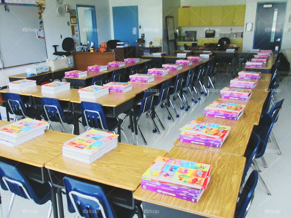 Elementary classroom. Bright colored books 9n desk ready for first day of grade school