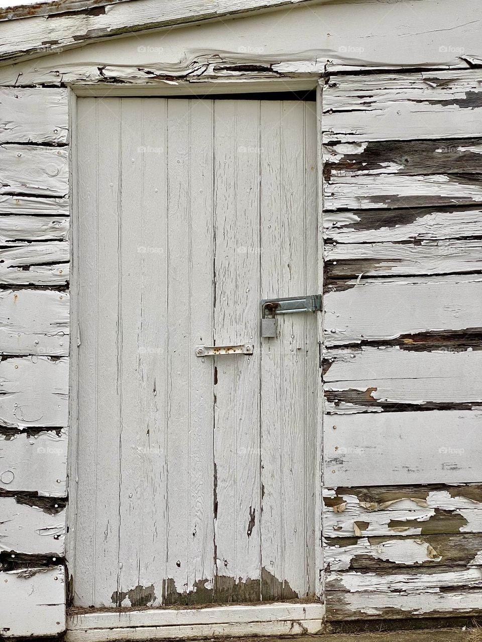 Peeling paint on a white painted outbuilding on a farm