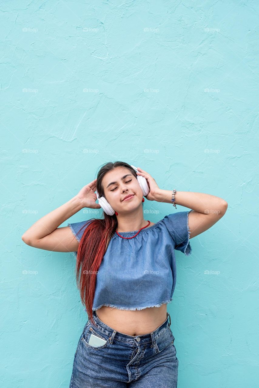 woman listening to the music against blue wall