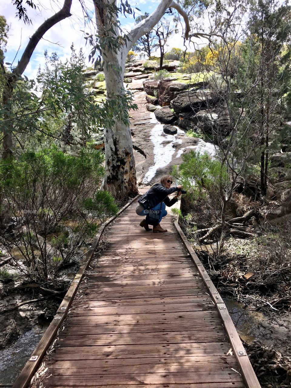 Flinders Ranges, Foap photographer (me) female crouching low to capture a shot with her camera on nature trail 