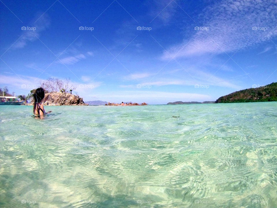 Girl swimming in an island  in Paradise with people in Sandbar
