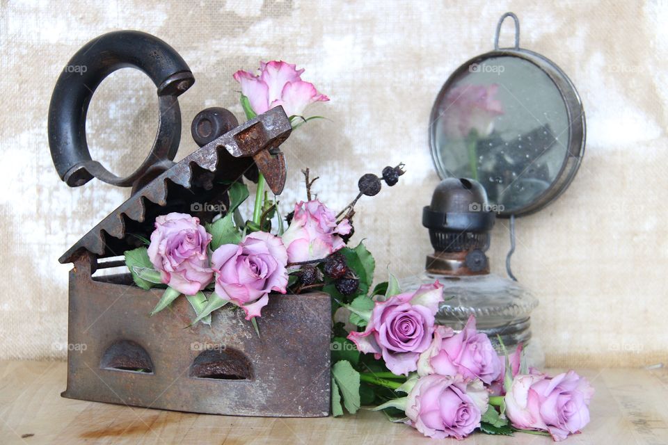 Pink roses in a iron and an old oil lamp