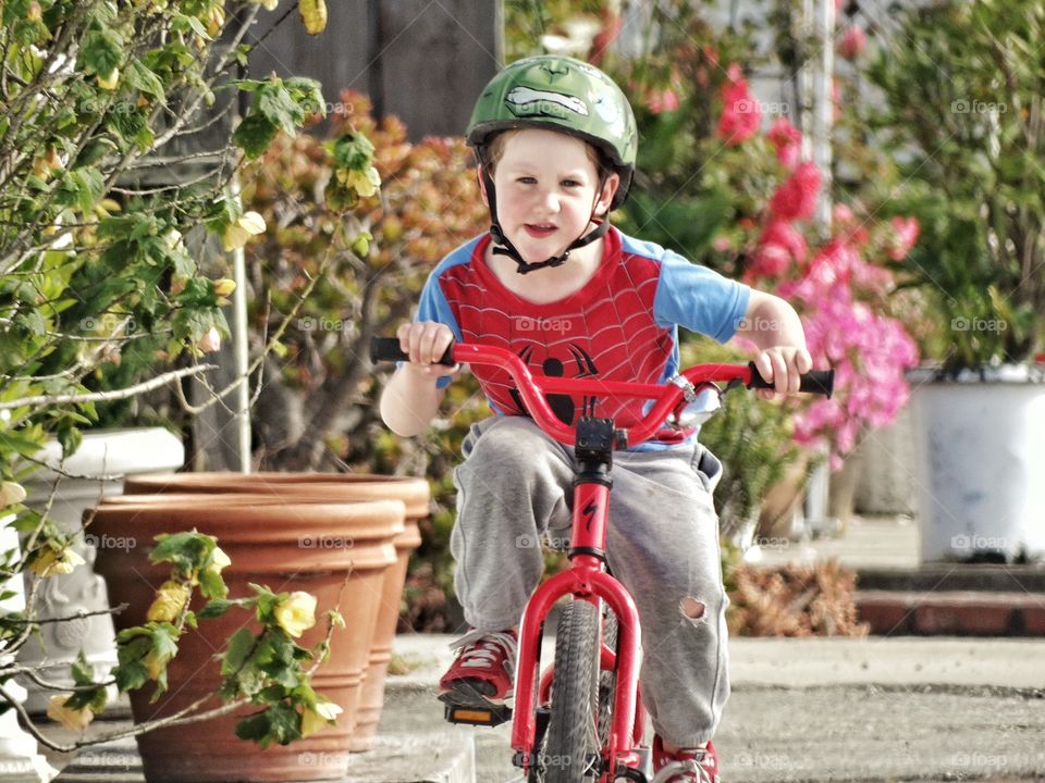 Young Boy Racing His Bike. Smiling Boy Racing His Bicycle Down The Sidewalk
