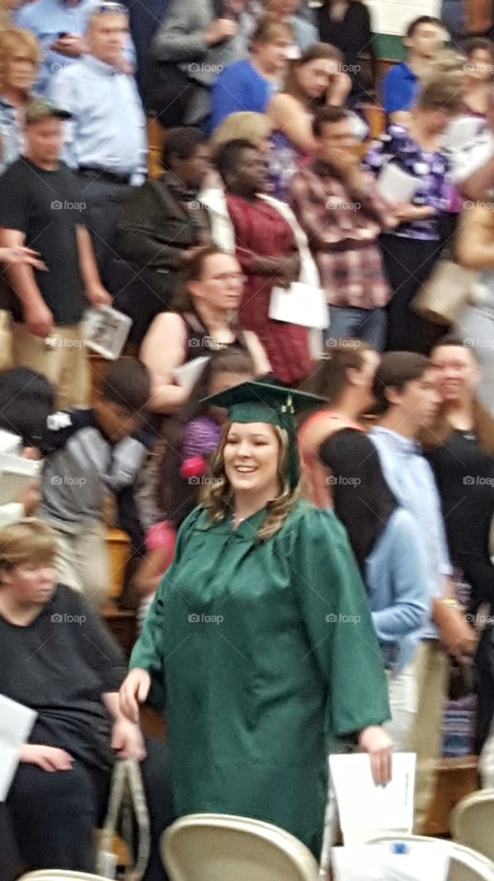 Happy graduate woman walking in crowd of people