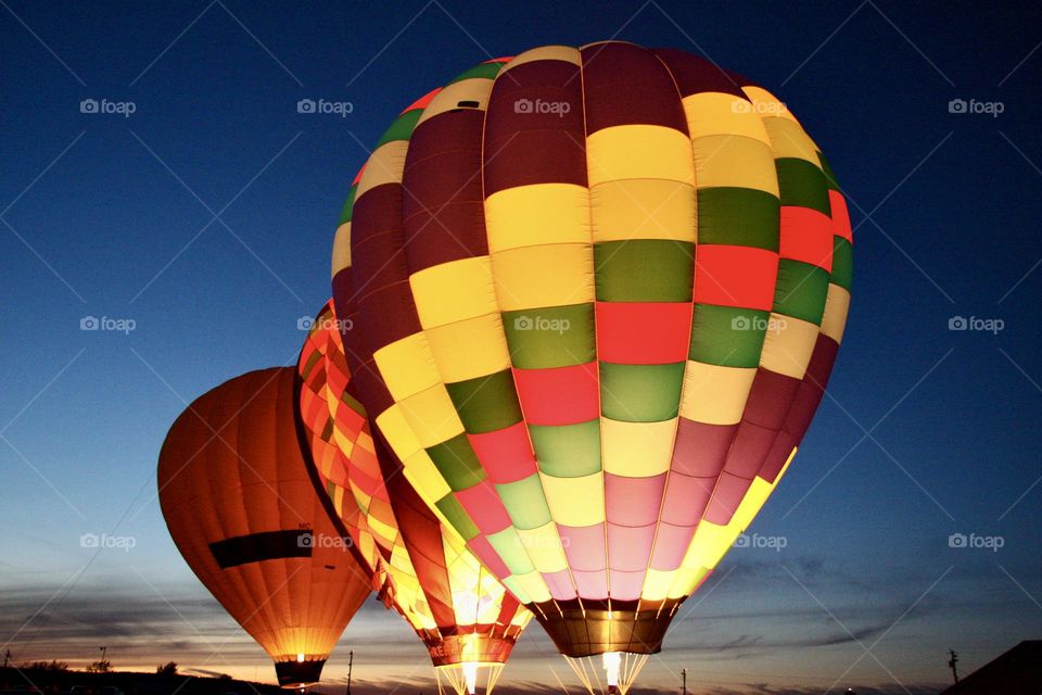 A line of colorful balloons illuminate in the evening of a balloon festival.