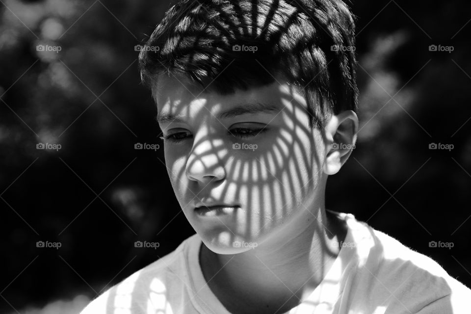 Shadows make design on face of boy in black and white