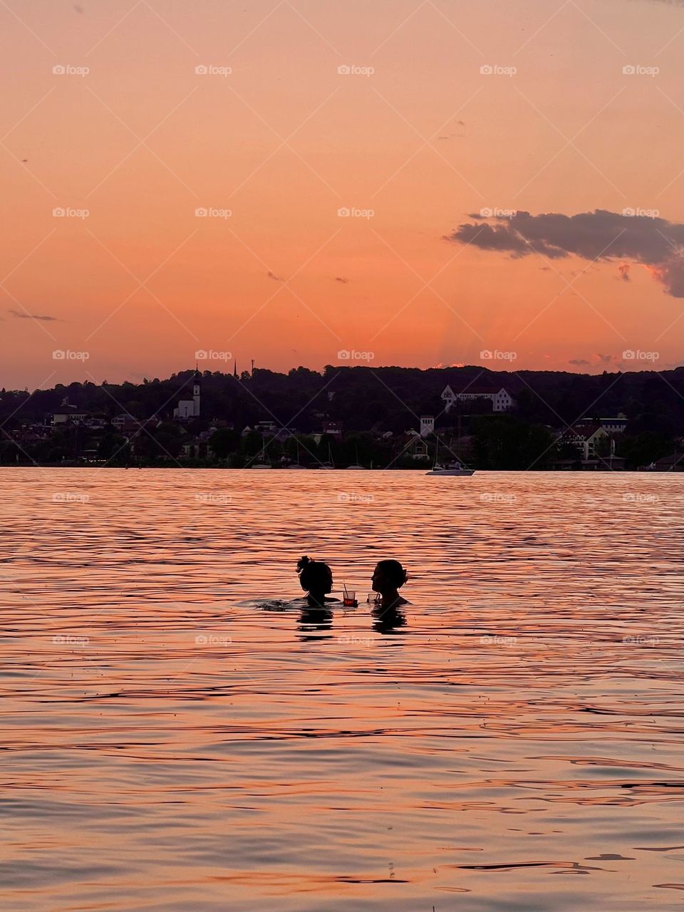 Summer Sunset Cheers. Golden hour bliss — two girls, cocktails in hand, enjoy a glowing sunset while floating in the calm lake. A perfect summer memory.