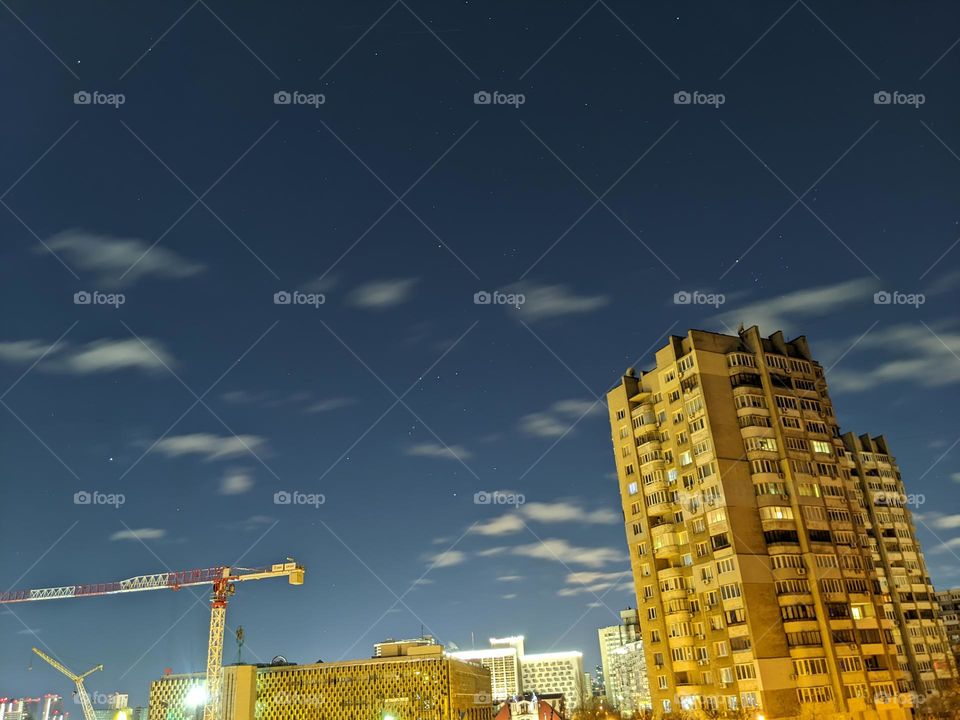 night sky with stars and clouds on the background of a residential building