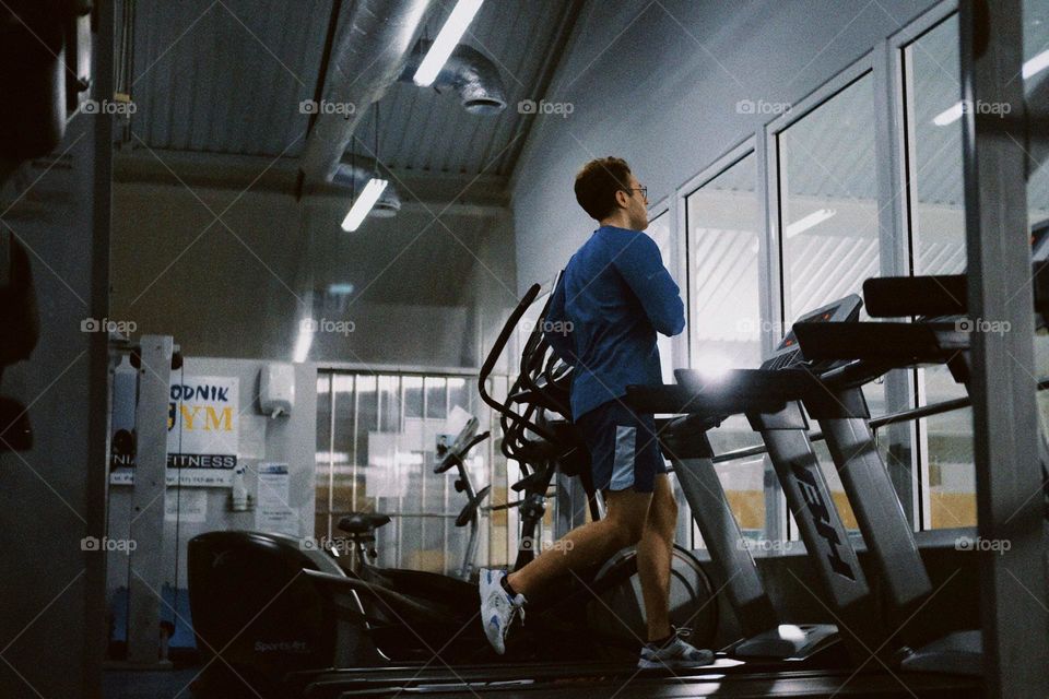 A young man running on a treadmill in the gym