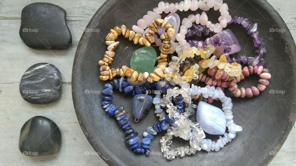 Gem stones in a black bowl on a rustic  grey wooden background with zen stones