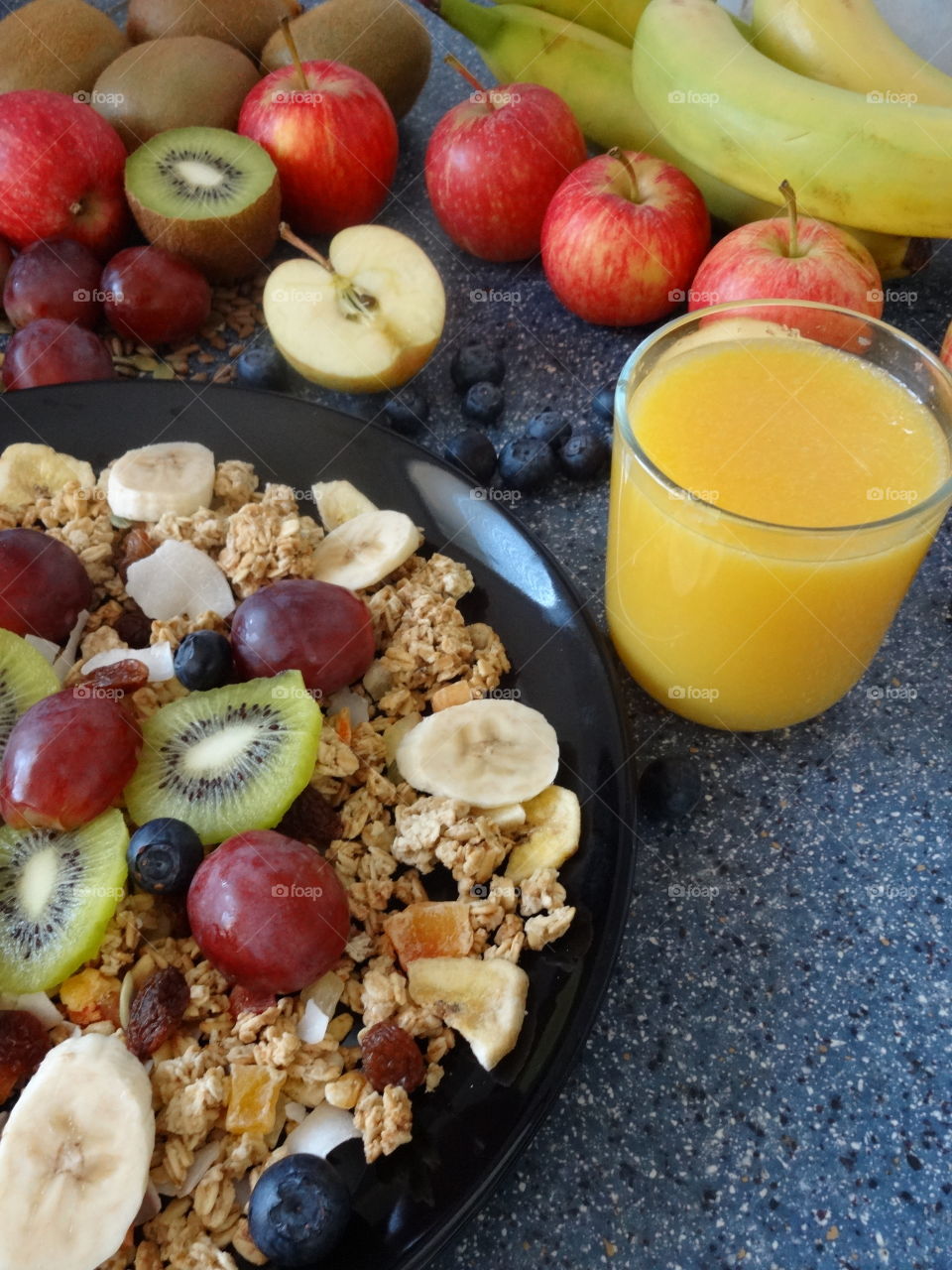 Healthy breakfast of crunchy flakes kiwi, banana, grapes, berries, raisins and fresh orange juicy drink