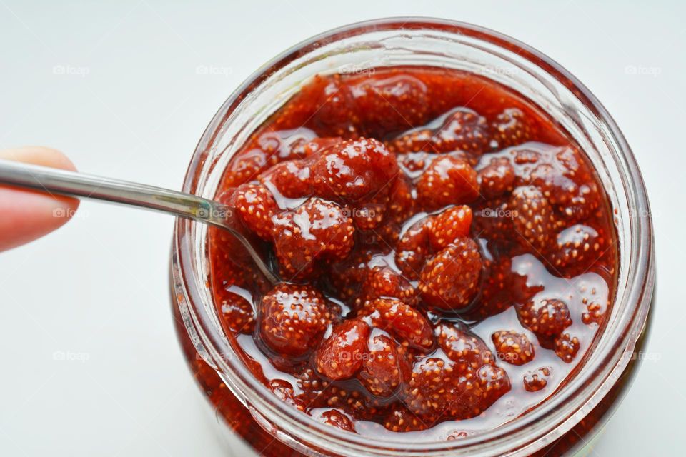 cooking handmade wild strawberry jam in bank and hand magenta colour