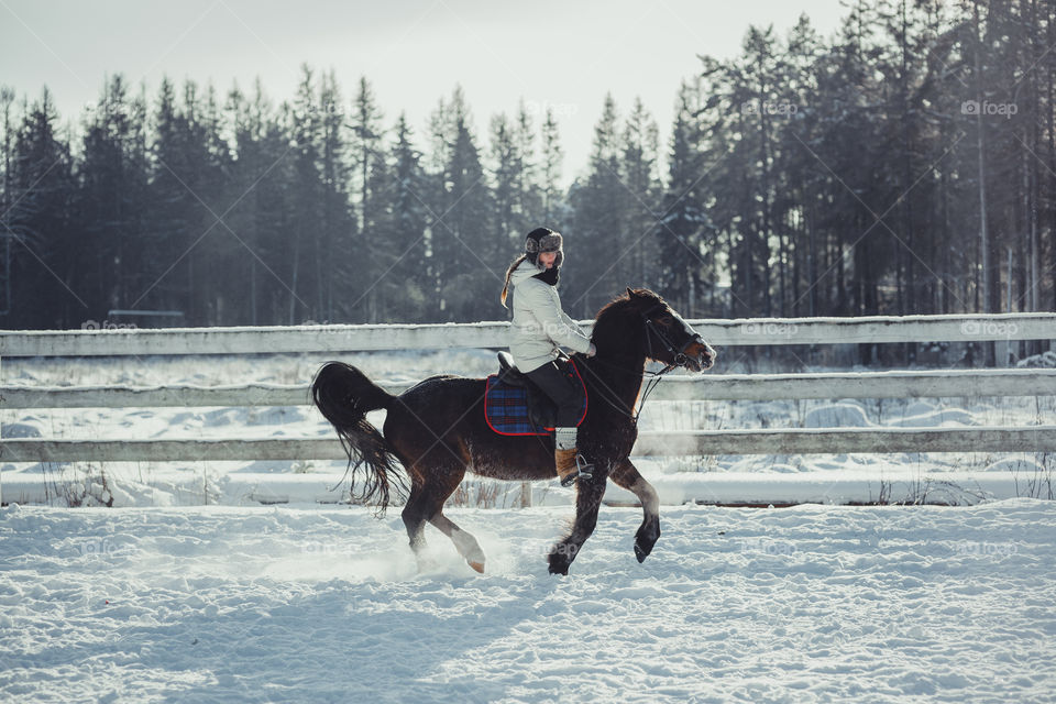 Teenage girl horseback jumping at cold winter day