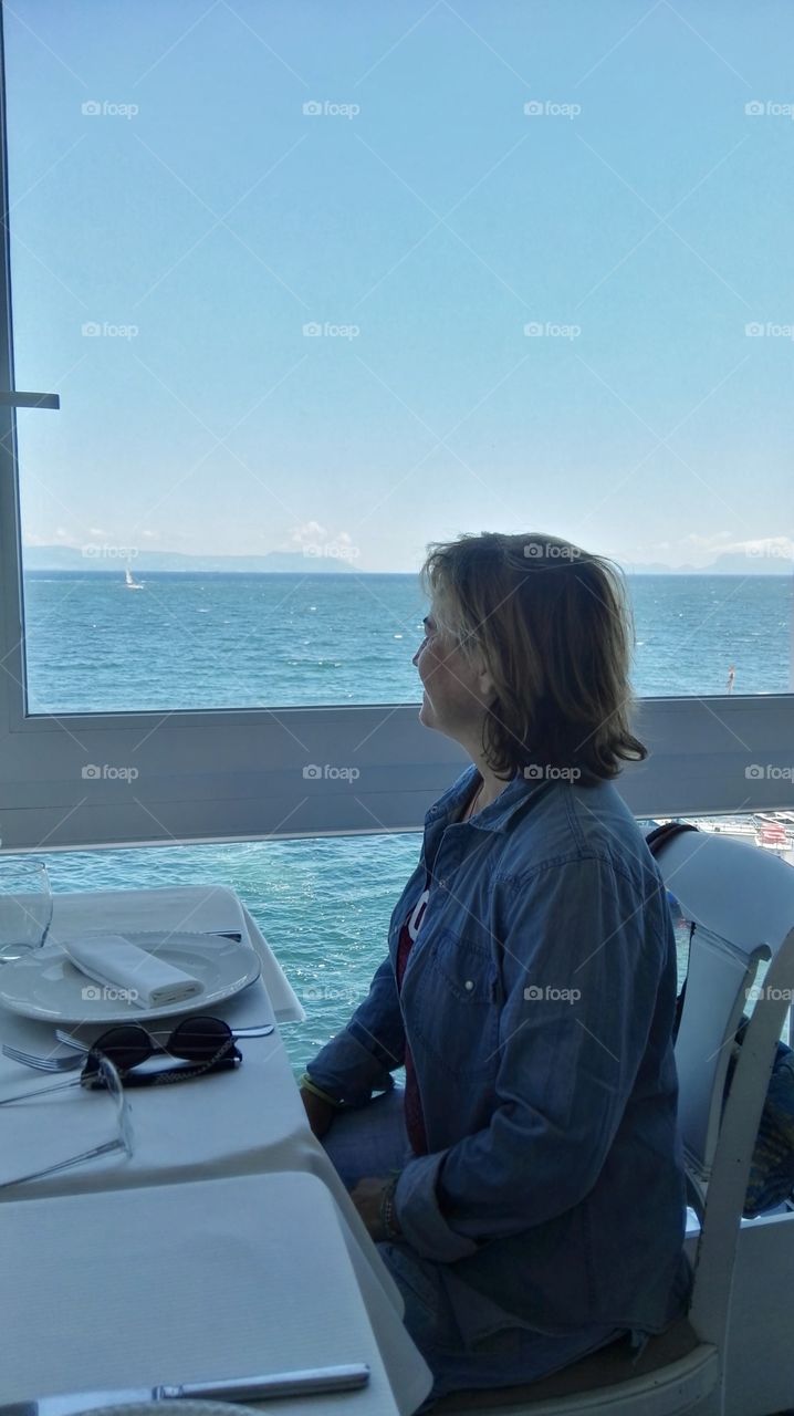 Woman looking the sea through the window 