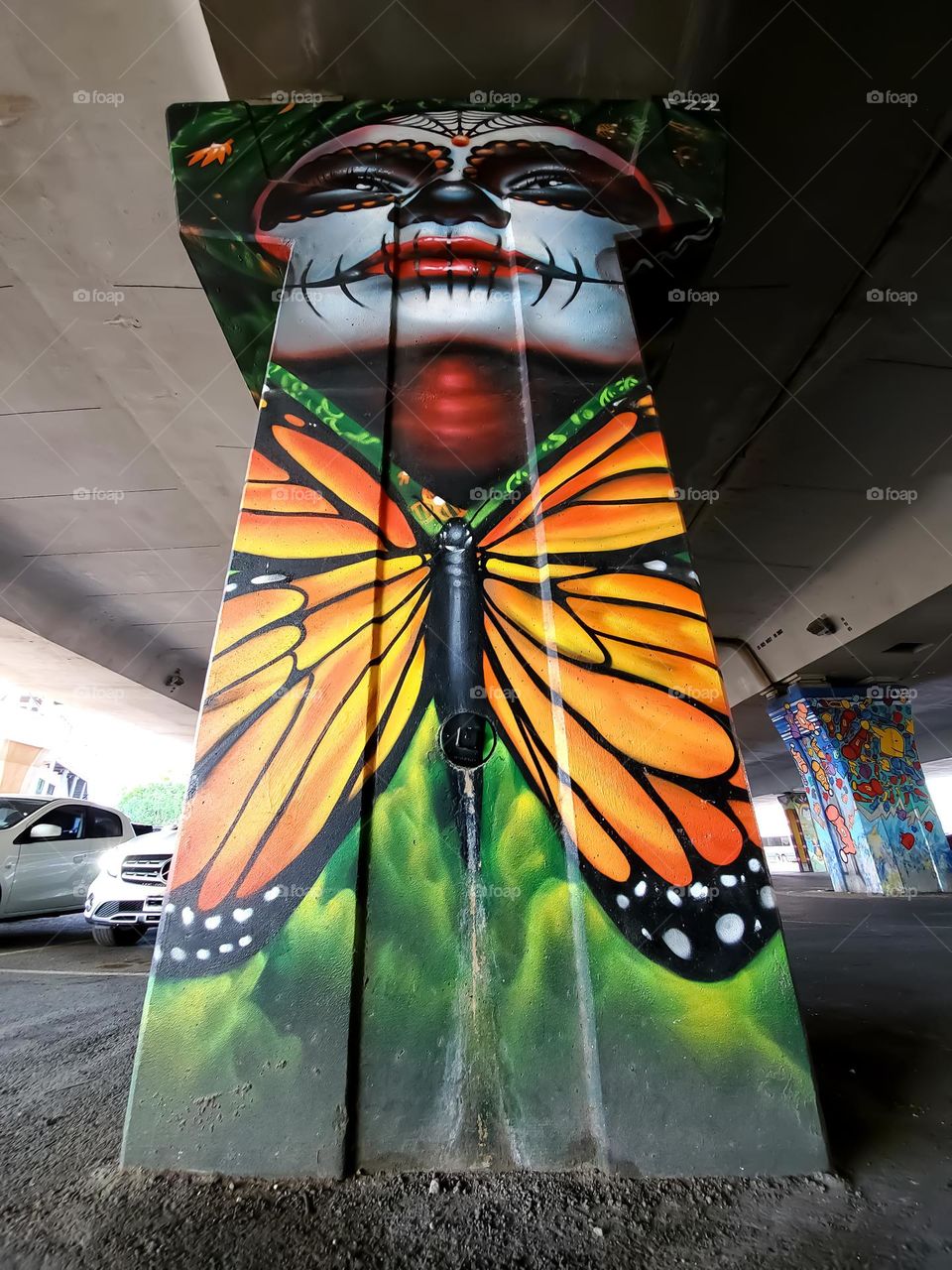 Ground view of street art on a cement highway pillar.