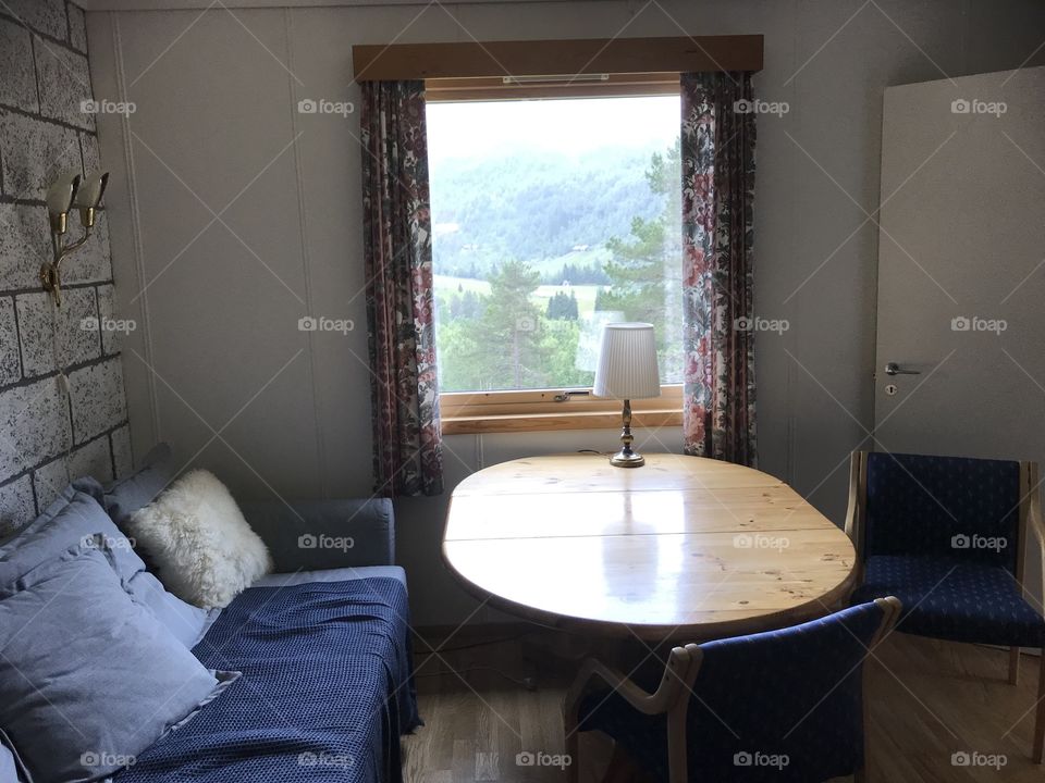 A typical mountain hotel / cabin in Norway. Here is shown a table, a sofa and some really not so great courtains.