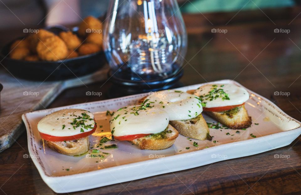  A plate of Delicious Bruschetta with tomatoes, mozzarella cheese and olive oil on a wooden table in a restaurant 