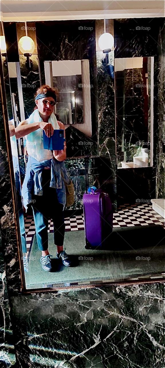 A new guest arrives at the „Pension Margrit“ in „Wilmersdorf“, „Berlin“, Germany. The little touches in the foyer are uniquely special such as the black & white checkerboard tile floor, white marble stairs and mirrors. 2023. Hypnotic Productions