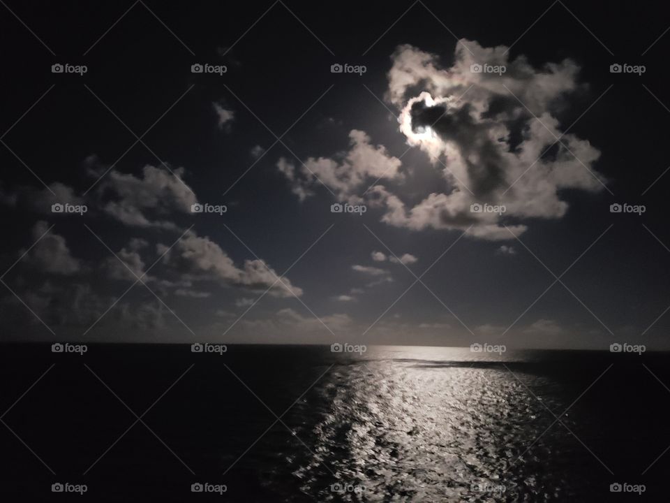 Moon in the clouds above the ocean