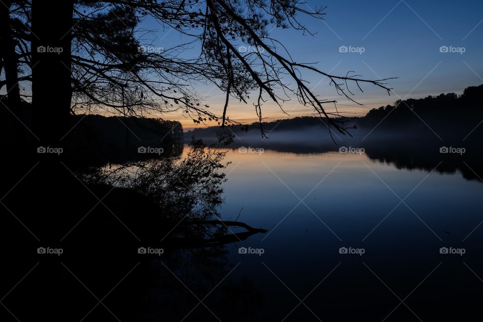 Slightly foggy twilight shot of Lake Benson is on a calm tranquil morning just before sunrise. Lake Benson Park in Garner North Carolina. 