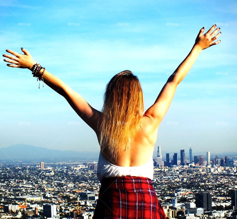 Girl holding her arms wide open expressing freedom free overlooking the city of Los Angeles from Runyon canyon