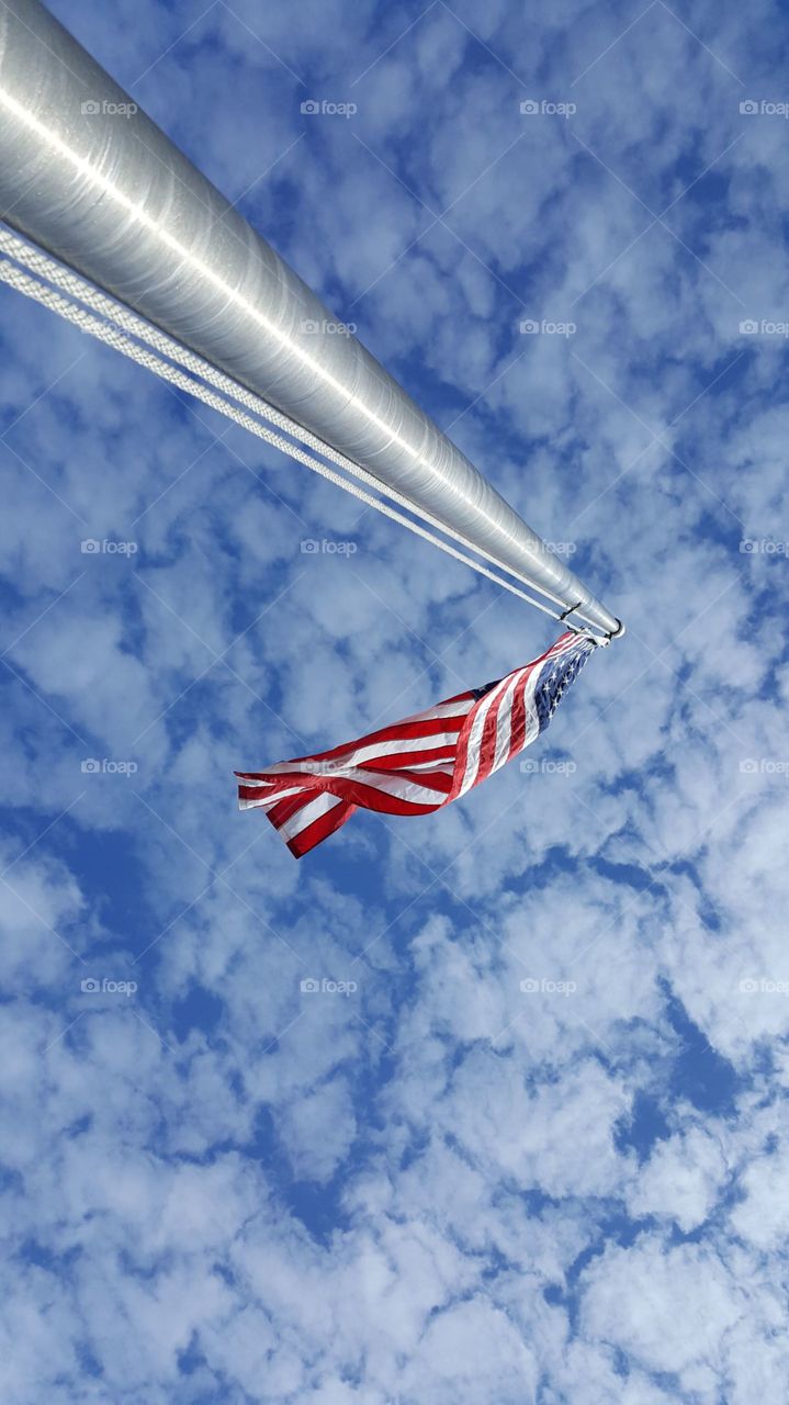 A United States American flag flying against a big blue beautiful sky.