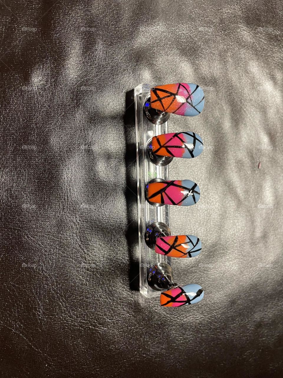 Blue, orange, and pink nail set with black stripes.