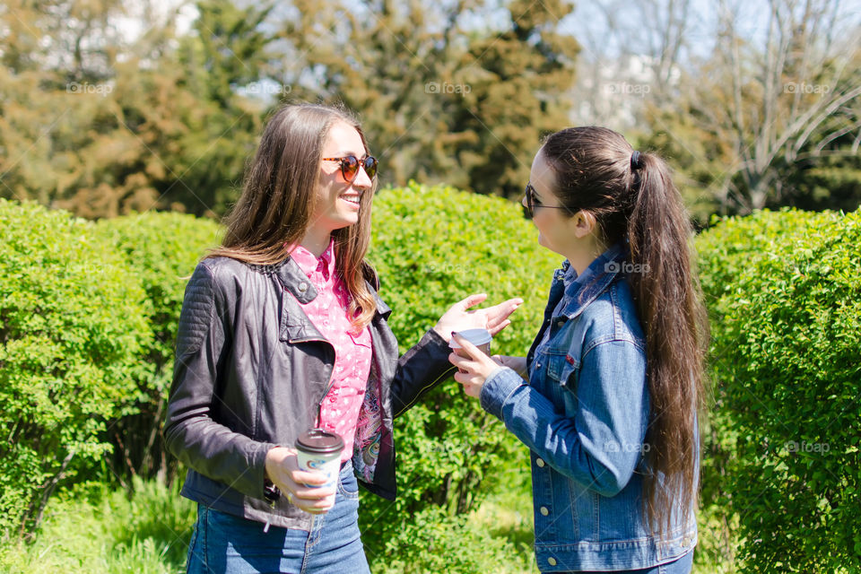 two friends drink coffee and have fun in the park