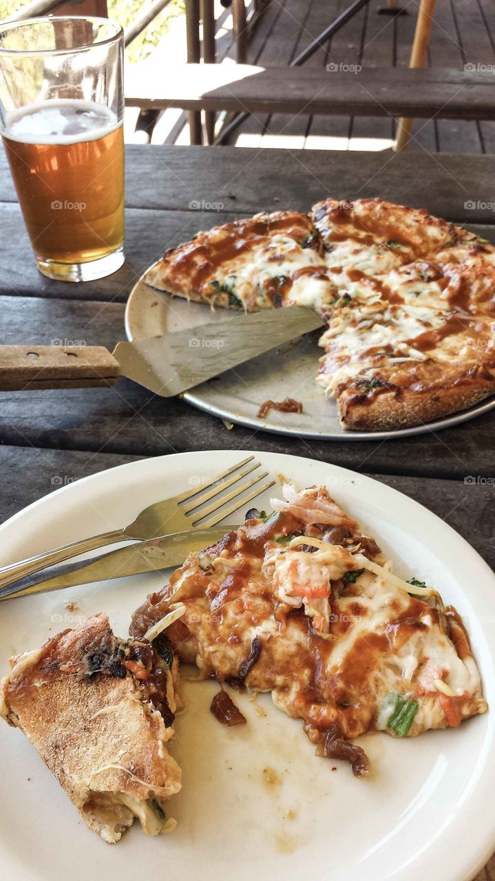 Thai Plpizza with a pint of beer on a picnic table.