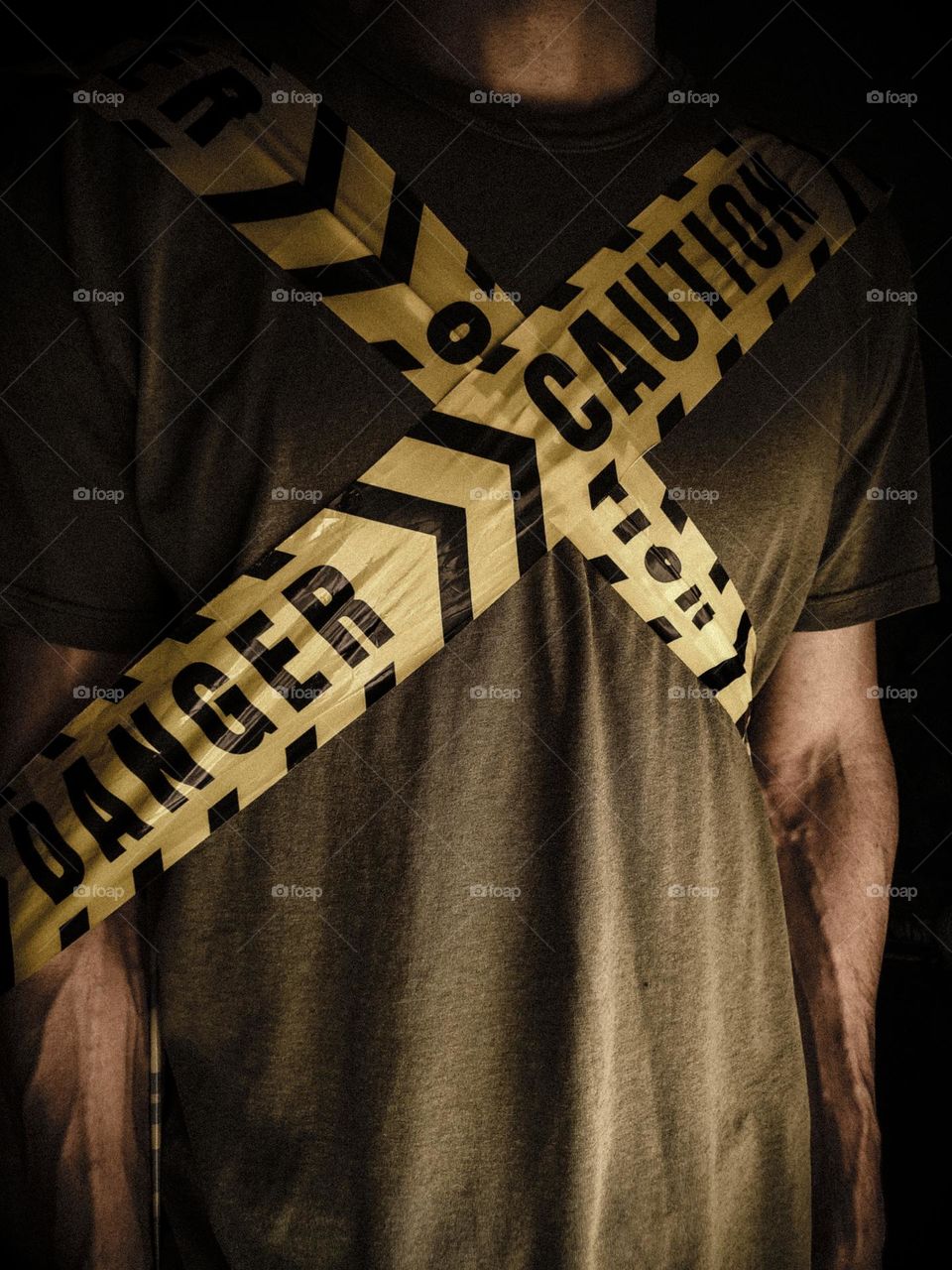 Man with danger and caution yellow tape in an X shape around his chest.