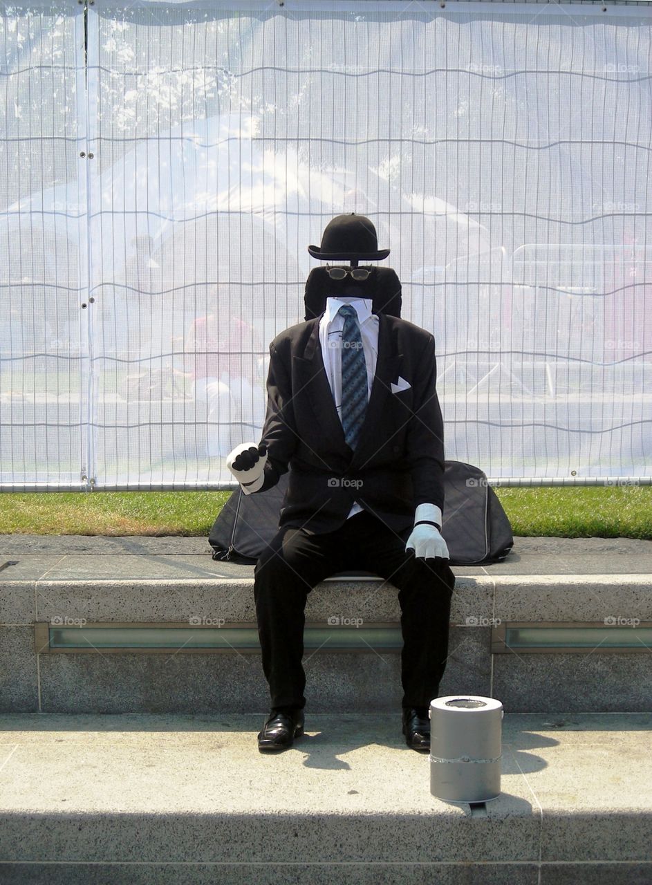 a person with suit hat and tie seated  without head