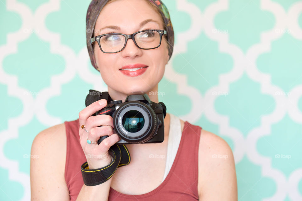 Young woman smiling and holding a DSLR camera