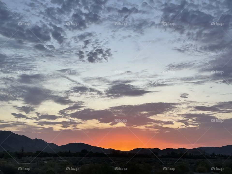 A orange and pink sunset with mountains and clouds.