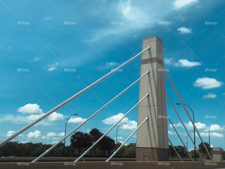 Big solid concrete cement pole structure on the road held by four perpendicular large long metal Rod or studs on each side between two road lanes on the highway.