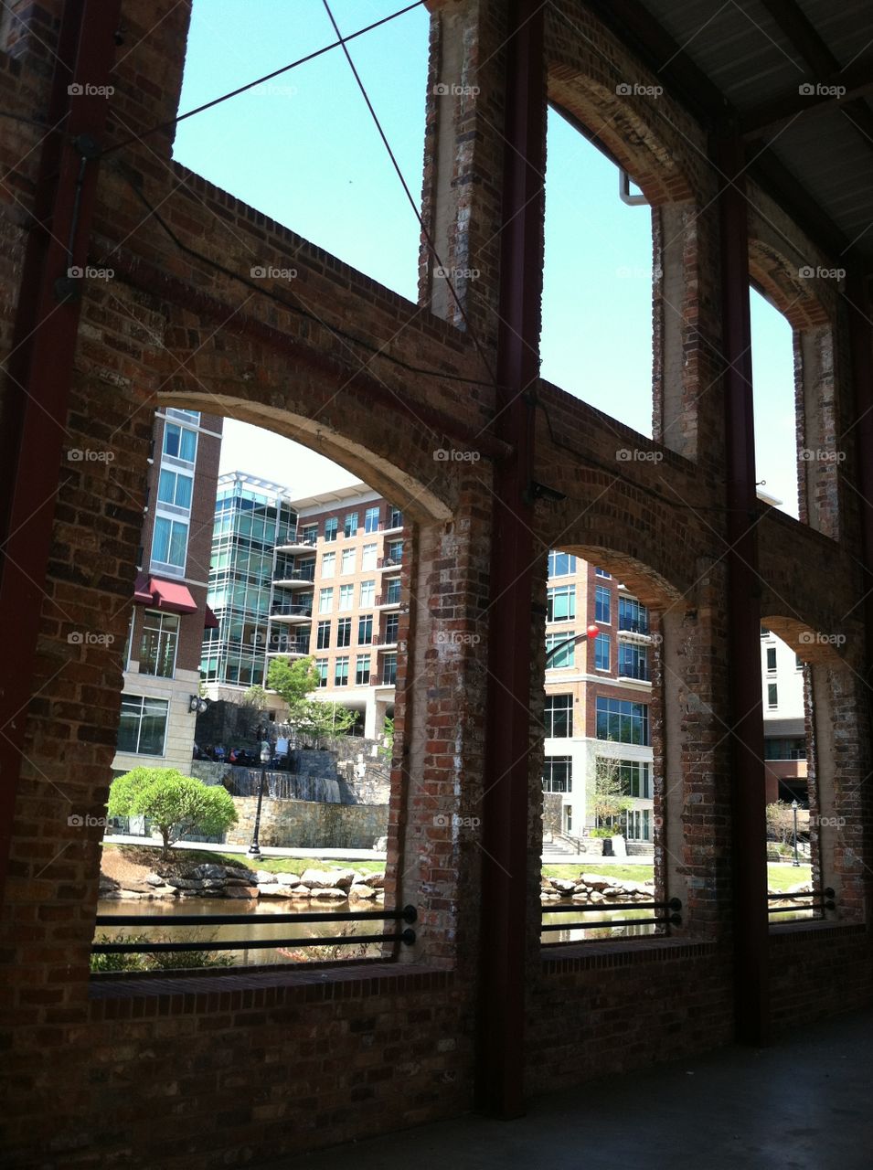 Arched windows of a historic brick building silhouetted against a modern city scene.