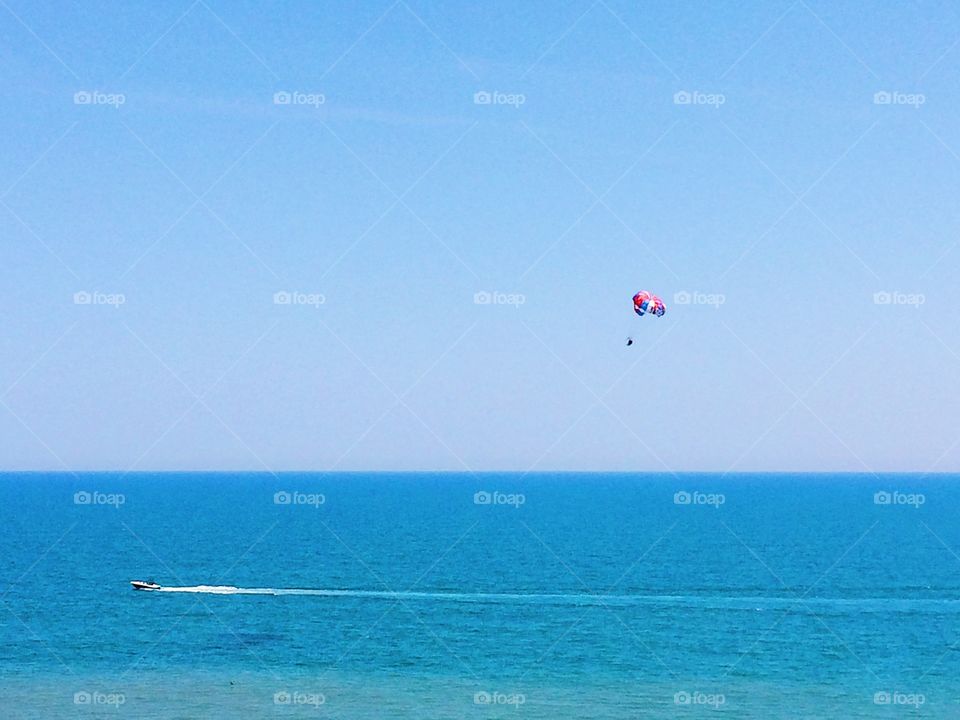 Minimalistic ocean view of parasail and speed boat